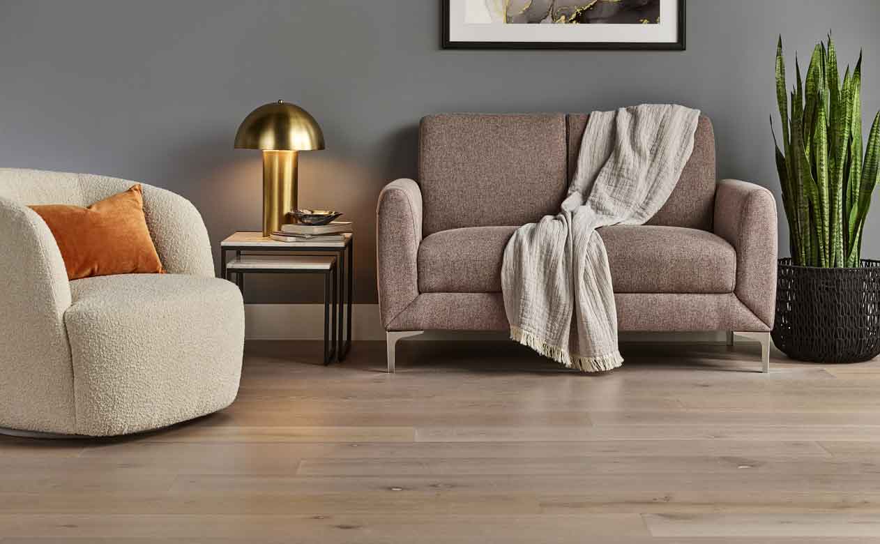 Hardwood flooring in a living room with brown sofa and beige accent chair